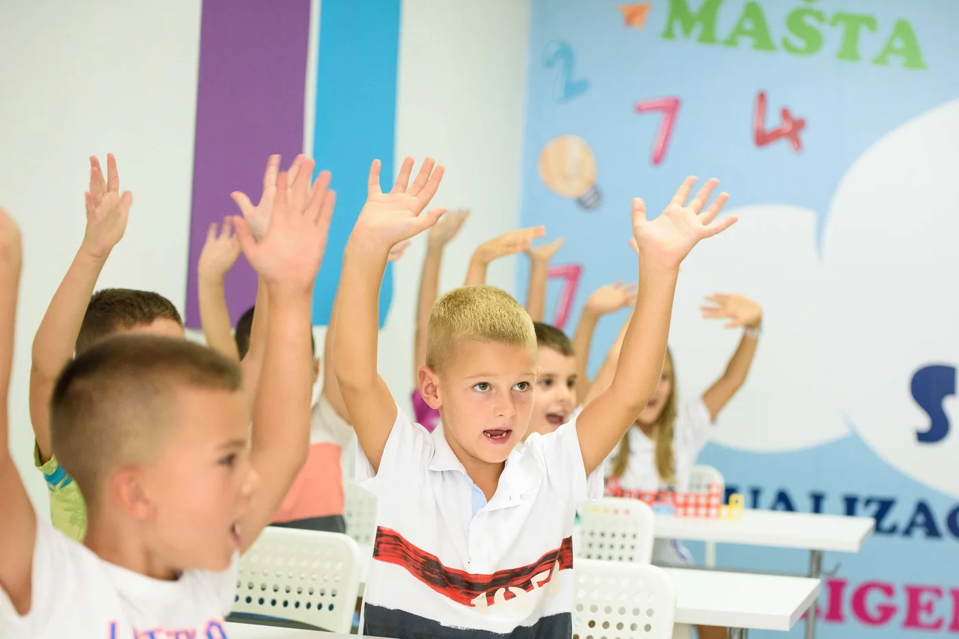 Children raising their hands to answer in class