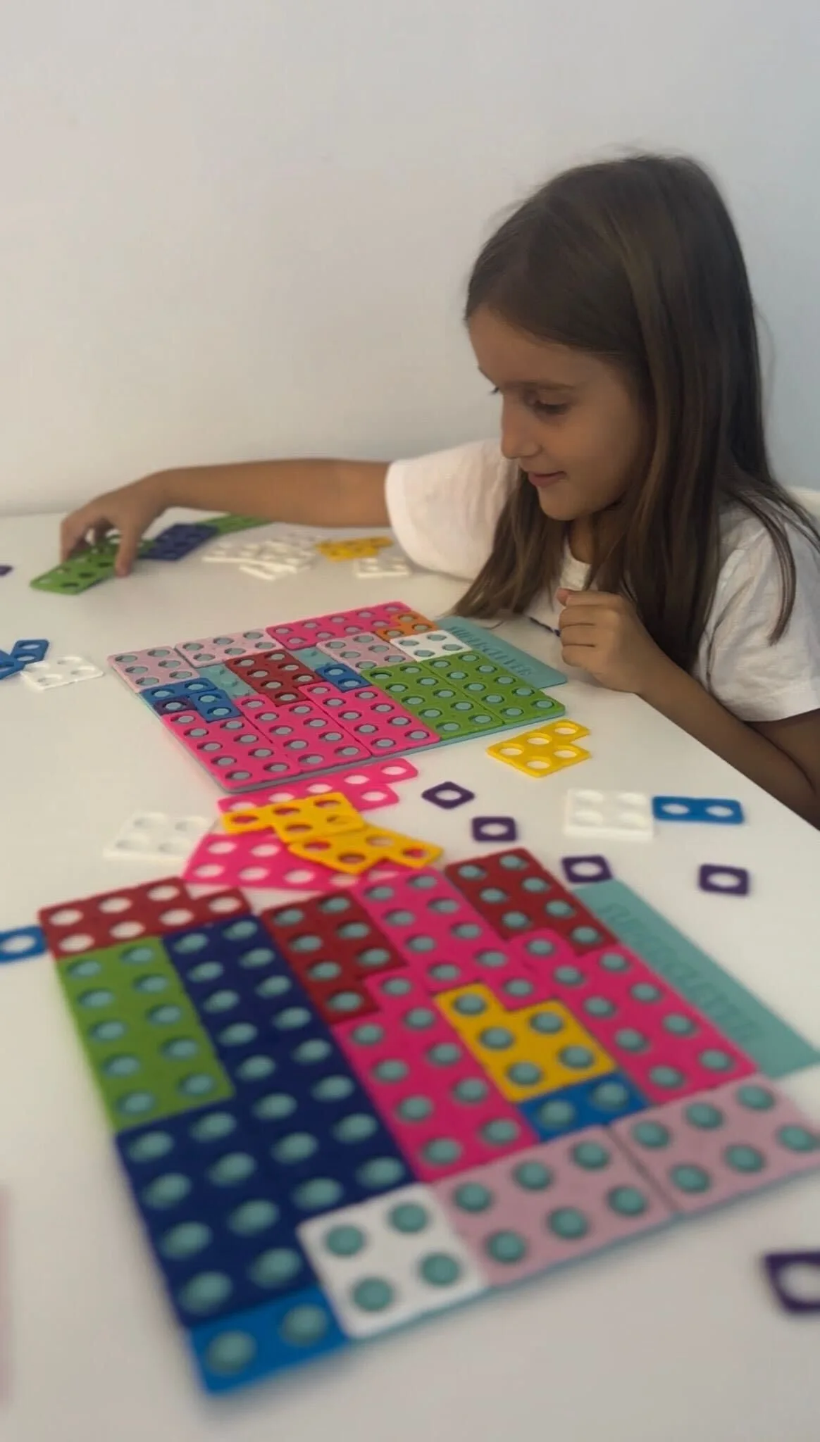 A girl building number tiles from the SuperClever set with her hands